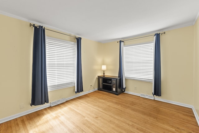 unfurnished room with wood-type flooring, plenty of natural light, and crown molding