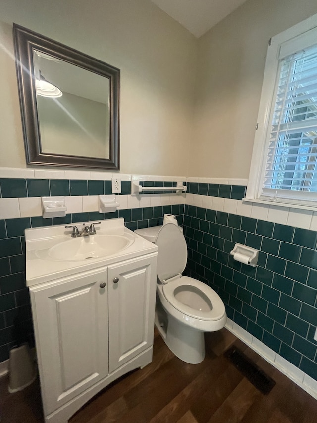 bathroom featuring tile walls, wood-type flooring, vanity, and toilet