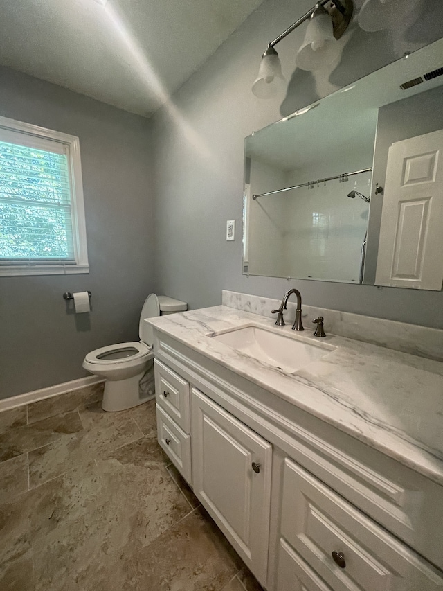 bathroom featuring a shower, vanity, and toilet