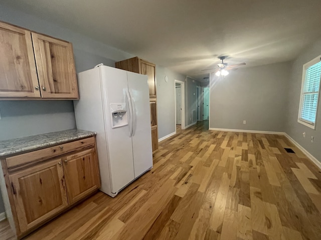 kitchen featuring ceiling fan, light wood-type flooring, and white fridge with ice dispenser