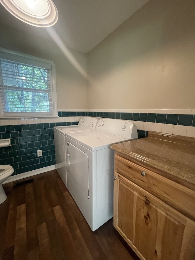 laundry area featuring tile walls, dark hardwood / wood-style floors, and washing machine and dryer