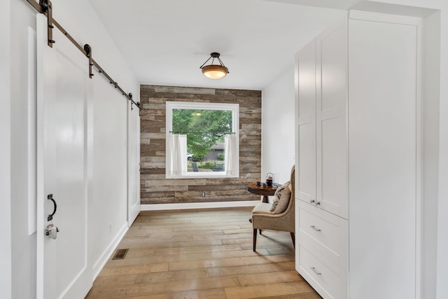 living area featuring a barn door, wood walls, and light hardwood / wood-style floors