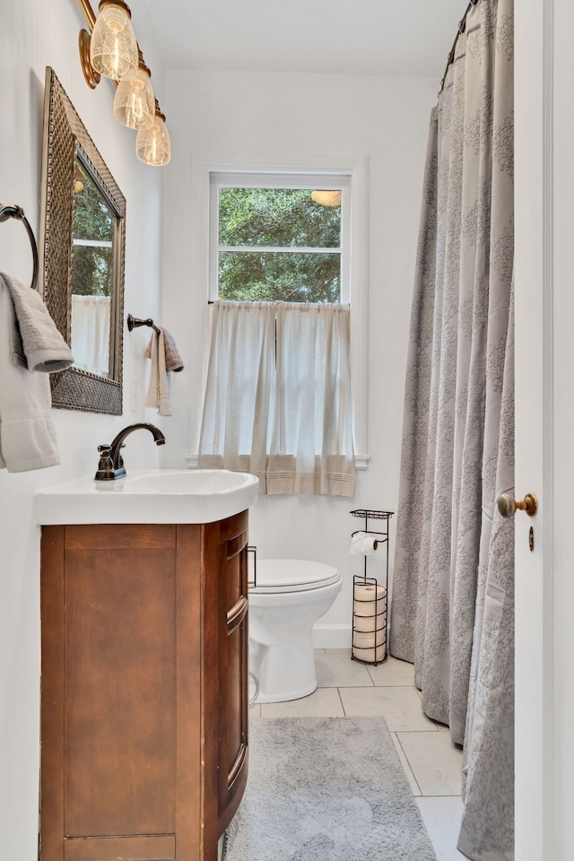 bathroom with a wealth of natural light, tile patterned floors, vanity, and toilet