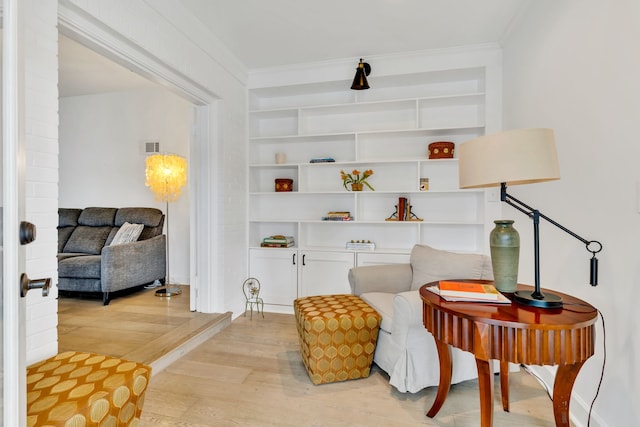 living area featuring light wood-type flooring and crown molding