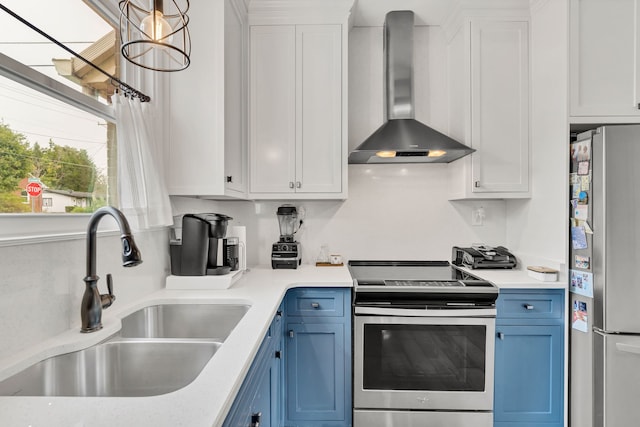 kitchen with stainless steel appliances, wall chimney exhaust hood, sink, white cabinetry, and blue cabinets