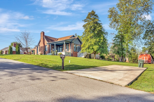 view of front of property featuring a front yard and a shed