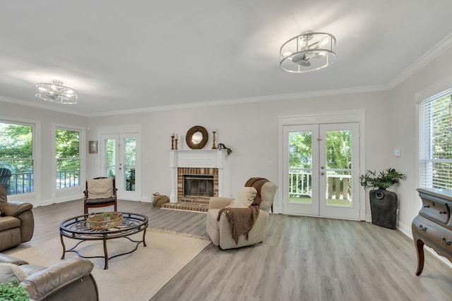 living room featuring light hardwood / wood-style flooring, a brick fireplace, a notable chandelier, and ornamental molding