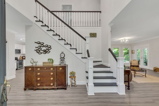 staircase featuring crown molding, hardwood / wood-style floors, and a notable chandelier