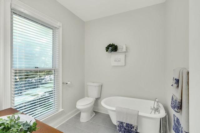 bathroom with a tub to relax in, plenty of natural light, toilet, and tile patterned floors