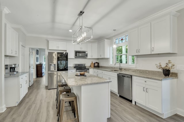 kitchen featuring hanging light fixtures, a kitchen island, light hardwood / wood-style flooring, white cabinetry, and appliances with stainless steel finishes