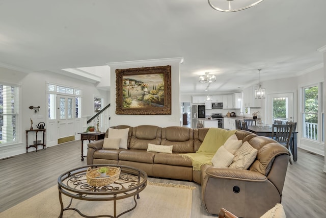 living room featuring crown molding, light hardwood / wood-style flooring, and a chandelier