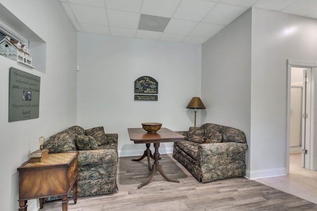 living area with light hardwood / wood-style flooring and a paneled ceiling