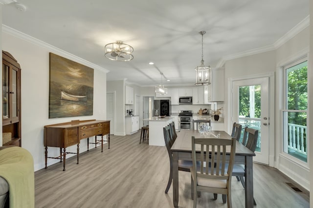 dining space featuring ornamental molding, light hardwood / wood-style floors, and a notable chandelier