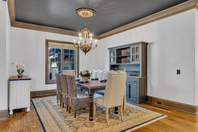 dining room with crown molding, hardwood / wood-style floors, and a notable chandelier