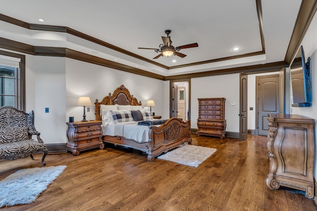 bedroom with ceiling fan, a raised ceiling, crown molding, and dark wood-type flooring