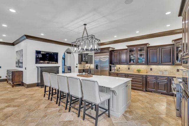 kitchen featuring tasteful backsplash, a kitchen bar, hanging light fixtures, a kitchen island, and stainless steel appliances