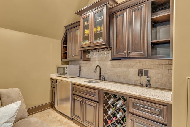 bar with light stone countertops, backsplash, sink, and stainless steel appliances