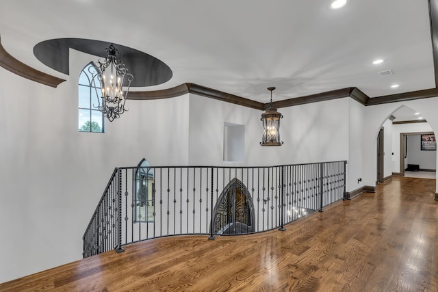 corridor featuring wood-type flooring, a notable chandelier, and ornamental molding