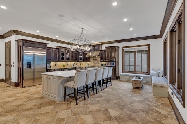 kitchen featuring hanging light fixtures, tasteful backsplash, a center island with sink, appliances with stainless steel finishes, and a kitchen breakfast bar