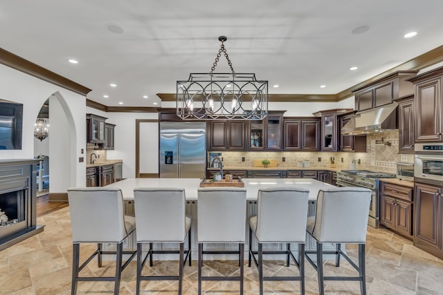 kitchen featuring high end appliances, a kitchen bar, a kitchen island with sink, and sink