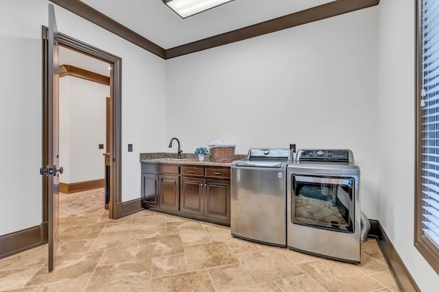 laundry area featuring crown molding, separate washer and dryer, sink, and cabinets