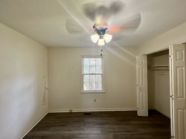 unfurnished bedroom with a textured ceiling, dark hardwood / wood-style flooring, ceiling fan, and a closet