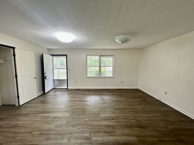 unfurnished room featuring a textured ceiling and dark hardwood / wood-style flooring