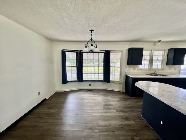 kitchen with a textured ceiling, a healthy amount of sunlight, dark hardwood / wood-style floors, and decorative light fixtures