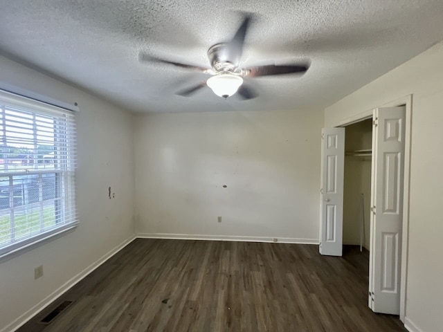 unfurnished room with ceiling fan, a textured ceiling, and dark hardwood / wood-style flooring