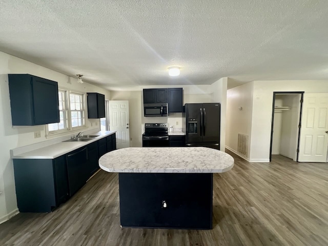 kitchen with a kitchen island, dark hardwood / wood-style floors, a textured ceiling, and black appliances