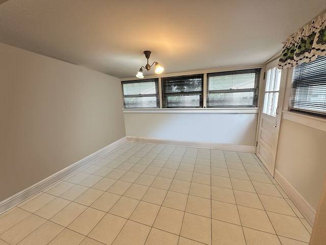 spare room featuring an inviting chandelier and light tile patterned floors