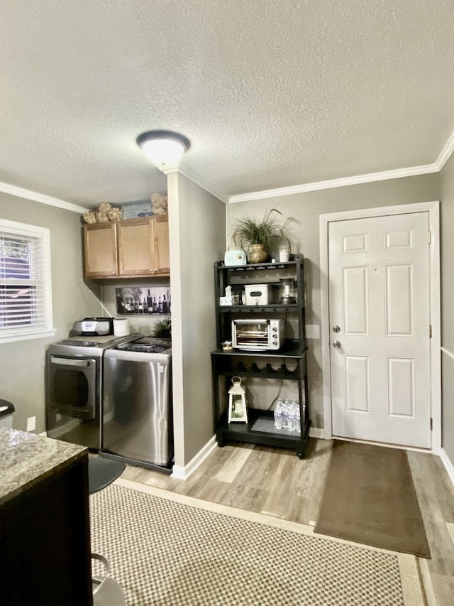 laundry room featuring cabinets, crown molding, light hardwood / wood-style floors, and washer and dryer