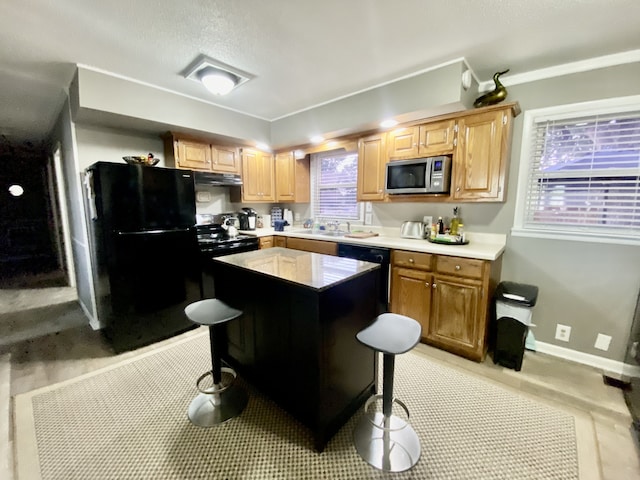 kitchen with black appliances, a center island, plenty of natural light, and sink