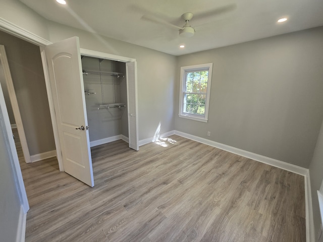 unfurnished bedroom featuring light hardwood / wood-style flooring, ceiling fan, and a closet