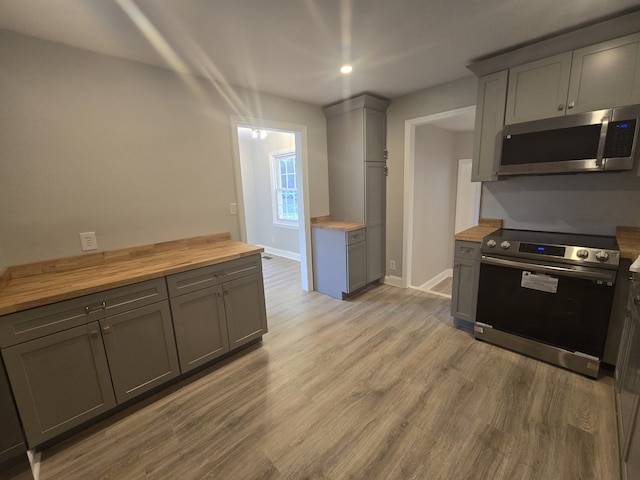 kitchen featuring light hardwood / wood-style flooring, stainless steel appliances, butcher block countertops, and gray cabinets