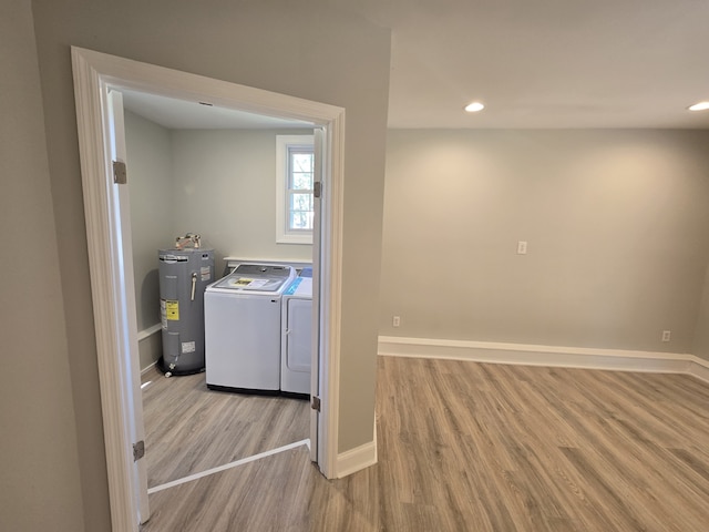 clothes washing area with electric water heater, separate washer and dryer, and light wood-type flooring