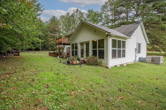 view of side of property with a sunroom, cooling unit, a deck, and a yard