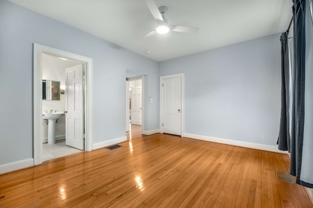 unfurnished bedroom featuring ensuite bathroom, sink, ceiling fan, and light hardwood / wood-style floors