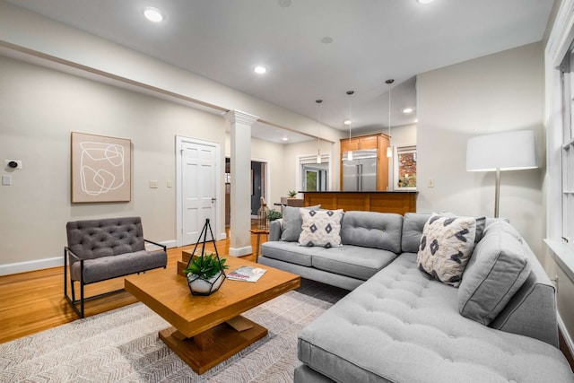 living room featuring decorative columns and light hardwood / wood-style floors