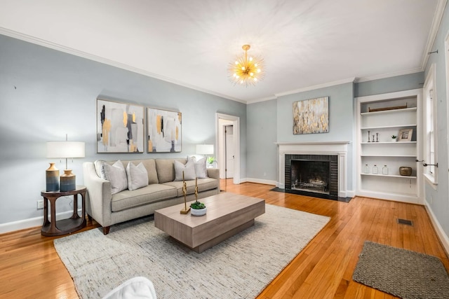 living room featuring a fireplace, light hardwood / wood-style floors, an inviting chandelier, and ornamental molding