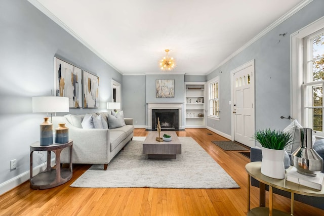 living room with wood-type flooring, ornamental molding, and a fireplace