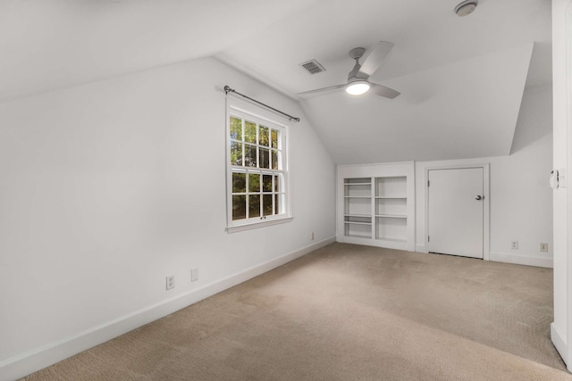 additional living space featuring light carpet, built in shelves, ceiling fan, and lofted ceiling