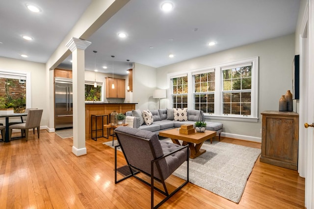 living room with decorative columns and light hardwood / wood-style flooring