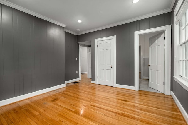 empty room featuring light wood-type flooring and crown molding