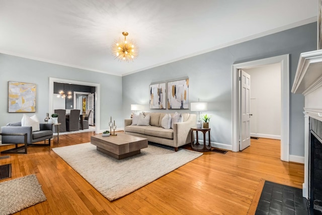 living room featuring a notable chandelier, wood-type flooring, and ornamental molding