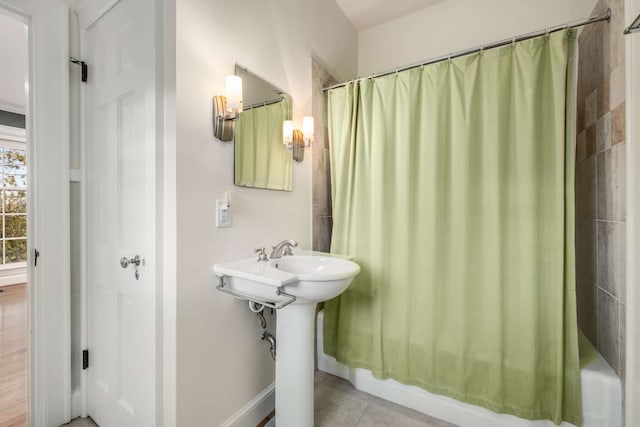 bathroom featuring tile patterned flooring, shower / bathtub combination with curtain, and sink