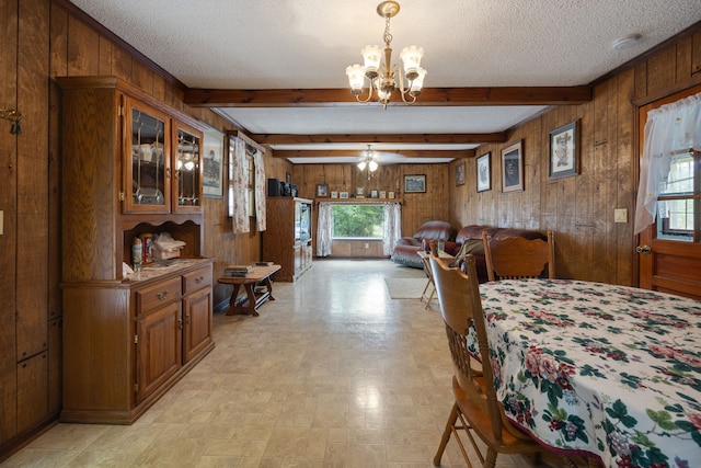 dining area featuring beam ceiling, wooden walls, and a wealth of natural light