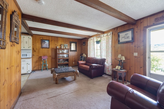 carpeted living room featuring a textured ceiling, wooden walls, and beam ceiling