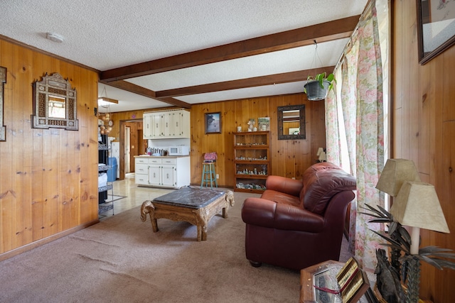 living room featuring light carpet, beamed ceiling, wood walls, and a textured ceiling