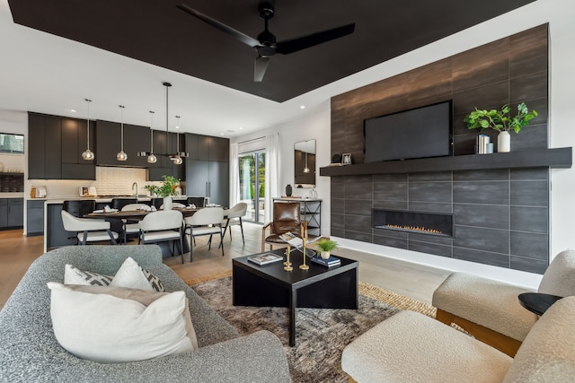 living room with light wood-type flooring, a fireplace, a ceiling fan, and recessed lighting